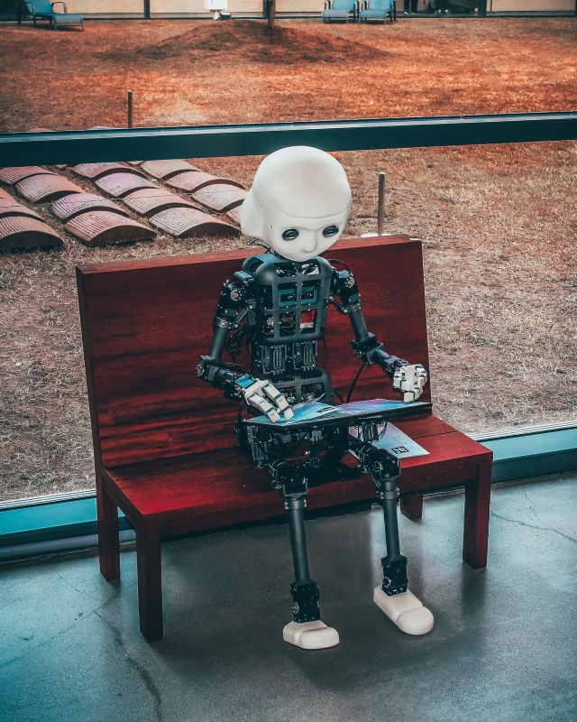 robot sitting on a bench reading a book